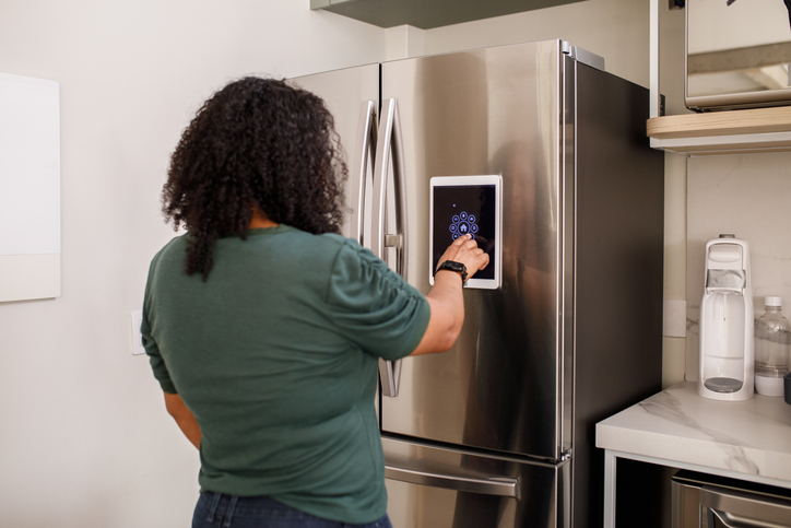 Woman operating smart refrigerator in a home setting. 